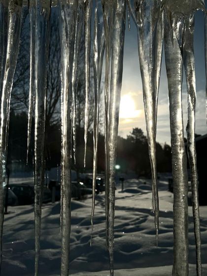 Icicles frame a view of the snowy landscape, capturing the essence of an Arctic winter expedition.
