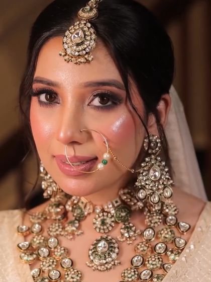 A close-up showcasing a stunning reception look. The makeup features a dramatic winged liner, shimmering glitter on the eyelids, and a glossy nude lip. The skin is kept dewy and highlighted to catch the light beautifully.