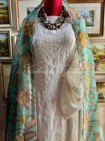 We present a complete ensemble that embodies understated luxury. This look pairs an exquisite off-white hand-embroidered Chikankari suit with our hand-painted Srikalahasti Kalamkari organza dupatta, creating a harmonious blend of two revered Indian crafts.