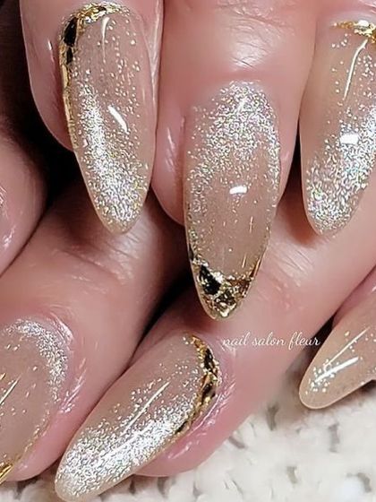 Festive nail inspiration: a shimmery cat eye base with gold foil accents at the cuticle and tip.