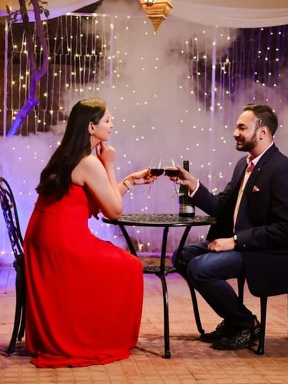 A glamorous evening look with a red dress and a romantic dinner setting. The makeup is bold and beautiful.