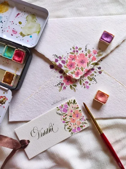 The process of creating one of the Guru Purnima tags, showing my watercolor palette and the delicate brushwork involved.