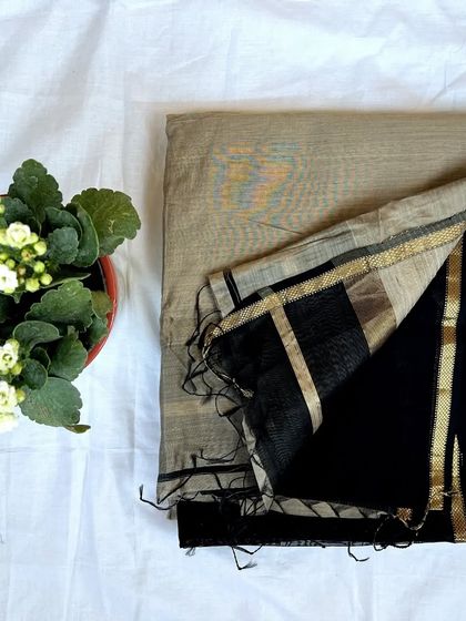 A subtle and elegant beige Maheshwari saree with a simple black and gold border.