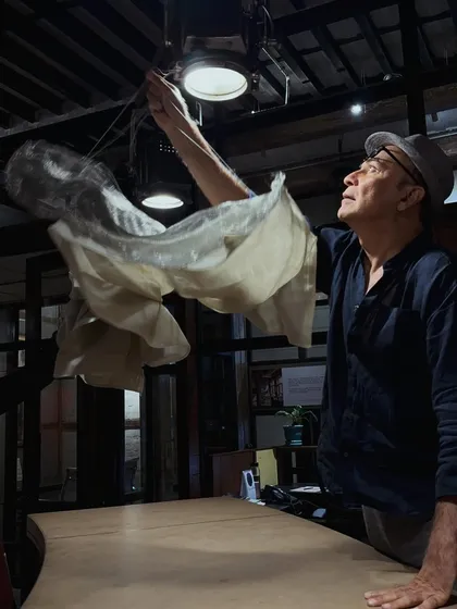A candid shot of Puran Kumar adjusting a custom light fixture, a moment of focused expression at The Loft.