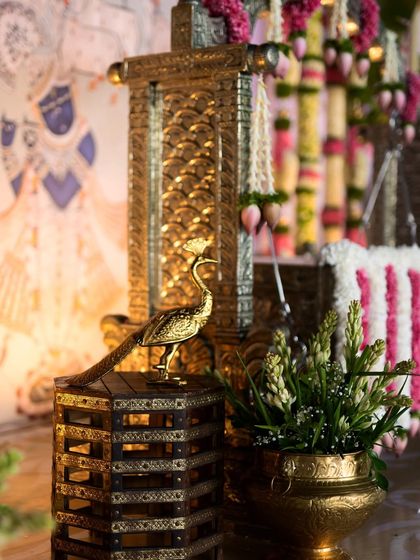 A beautifully crafted brass peacock perches on a wooden stand, overlooking the ceremony. These artistic elements add a touch of elegance and symbolism to the overall decor.