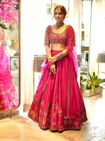 The final Mehendi look. The rich pink of the Ridhi Mehra lehenga paired with a contrasting green choker creates a look that is traditional yet refreshingly modern.