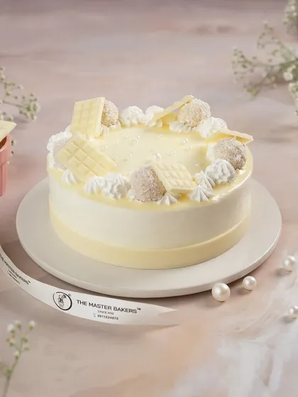 Our White Forest cake is a delicate and elegant dessert. It's adorned with white chocolate shavings, fluffy cream, and coconut-dusted truffles, making it a sophisticated choice for any occasion.