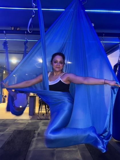 Wrapped in the silk, feeling graceful and strong. The vibrant blue fabric and the member's confident pose capture the empowering atmosphere of our studio.