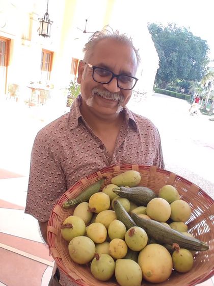 A farmer proudly holding a basket of freshly harvested gourds.