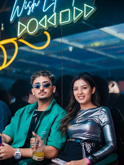 A couple enjoying drinks under the neon lights.