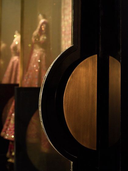 Another angle of the semi-circular door handle, showing its interaction with the store's interior. The reflection of the designer's couture in the glass creates a beautiful juxtaposition between fashion and functional hardware design.