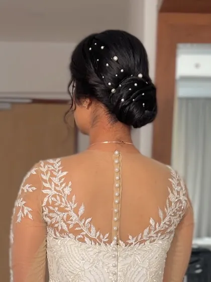 A sleek and modern bun adorned with scattered pearls. This is a chic and sophisticated look for a reception or cocktail party.