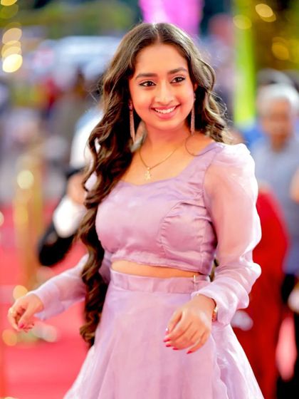 A candid, over-the-shoulder smile from Ankitha Jayarama, capturing a spontaneous moment.