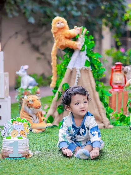An outdoor first birthday celebration with a jungle theme. The 'ONE' blocks and a small cake bring the party to the garden for a natural and fun milestone shoot.