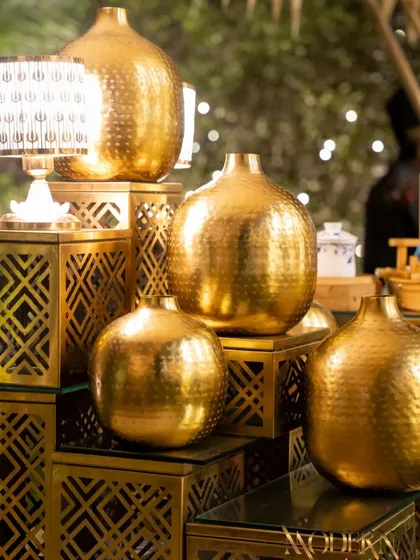 Hammered gold vases and geometric stands create a luxurious and modern Turkish-themed buffet. The warm lighting enhances the golden tones, adding to the opulent feel of the event.