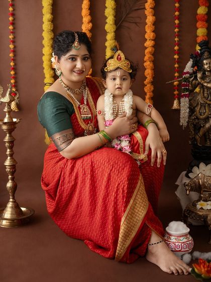 A classic, seated portrait of a mother and her son in their full festive attire, looking directly at the camera.