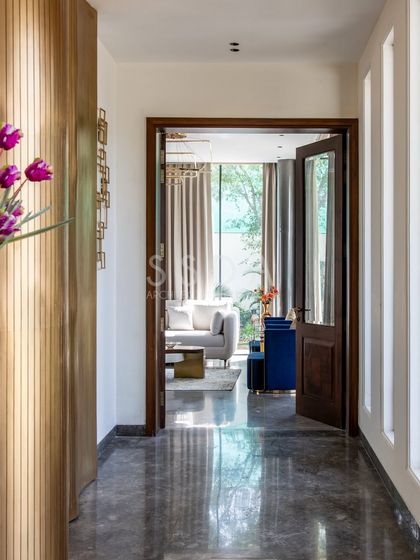 A view from the corridor into the living room of 'House Retold', showcasing how I use doorways to frame spaces. The polished marble floor reflects the natural light, leading the eye towards the bright, inviting living area.