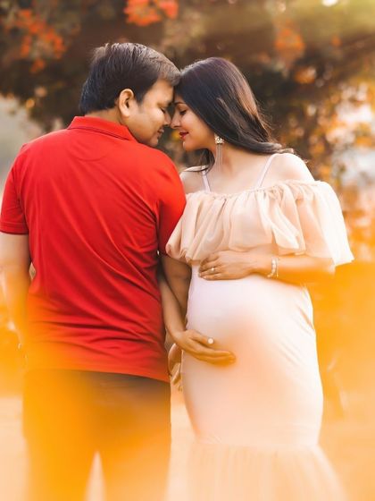 An intimate close-up of a couple, heads together, surrounded by the warm, golden light of sunset. This outdoor maternity photo is filled with warmth and affection.