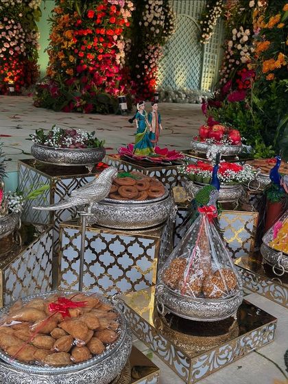 A close-up of the offering table, showing traditional sweets, silver bird props, and pineapple arrangements.