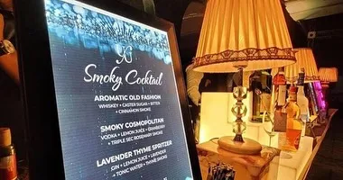 A close-up of our custom digital menu for a "Smoky Cocktail" station. We offer curated menus featuring drinks like the Aromatic Old Fashion and Smoky Cosmopolitan, complete with descriptions of their unique infusions.