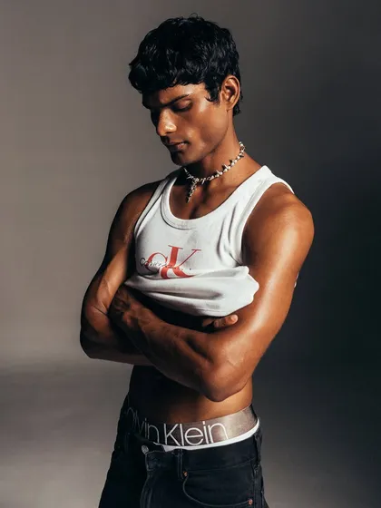 A quiet, introspective moment from the Calvin Klein shoot. The styling is minimal to emphasize the model's form and the classic appeal of the CK tank top, creating a timeless and authentic portrait.