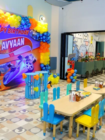 A vibrant Hot Wheels themed birthday setup. The bright orange and blue colors and dynamic car graphics create an exciting atmosphere for a young car enthusiast.