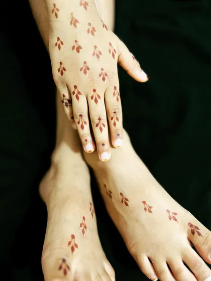 A minimalist design for both hands and feet, featuring small, scattered leaf motifs.