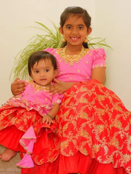 A close-up of these sweet sisters in their matching red and pink twinning outfits. It's the little details that make these sets so special.