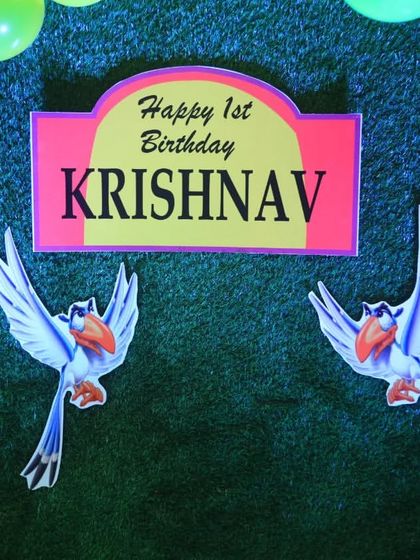 A close-up of the custom "Happy 1st Birthday" sign from the Lion King theme, featuring Zazu the hornbill.