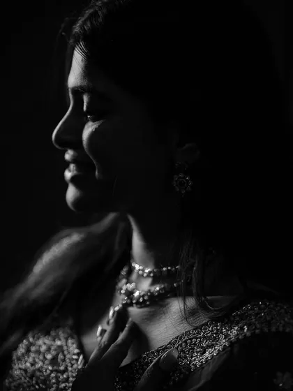 A soft, low-light portrait that feels incredibly intimate. We focused on capturing the gentle curve of the bride's smile and the delicate sparkle of her jewelry in this black and white photograph, creating a timeless and elegant feel.