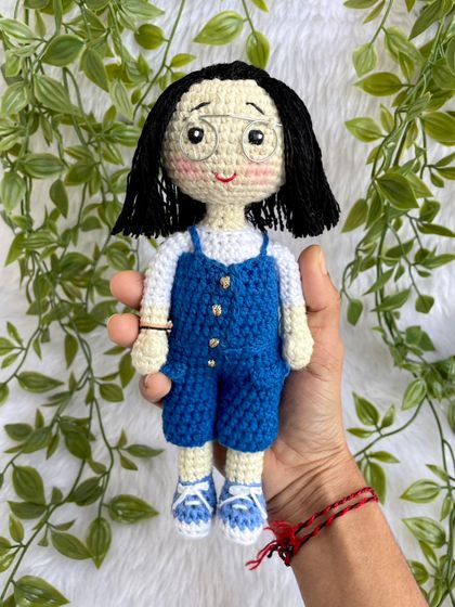 A lovely replica doll in a blue jumpsuit with matching shoes. The details, like her glasses and hairstyle, were carefully crafted to match the photos provided. These dolls can be made to stand on a wooden base.
