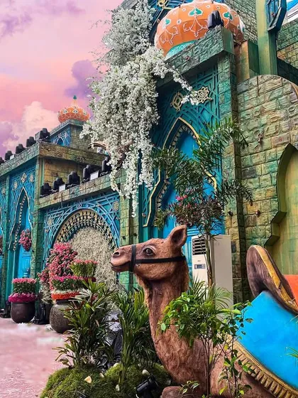 A daytime view of a Moroccan-inspired palace structure I built. The vibrant turquoise and terracotta colors, intricate tile work, and cascading white flowers create a stunning visual against the sky.