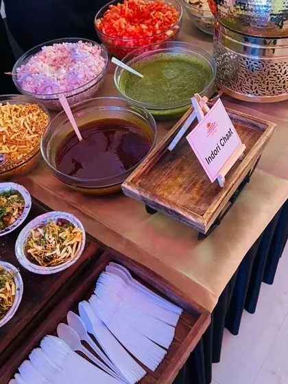 The complete setup for our Indori Chaat live station. All components, from the fried potatoes to the fresh chutneys, chopped onions, and sev, are neatly arranged for guests to customize their plate.