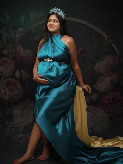 A regal pose in a teal satin gown, complete with a crown. This portrait is a reminder of the strength and beauty of the female body during pregnancy.