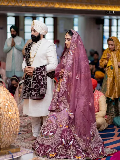 The couple stands together for the Ardaas, a moment of prayer and blessing. This photo captures the reverence and unity of the ceremony.