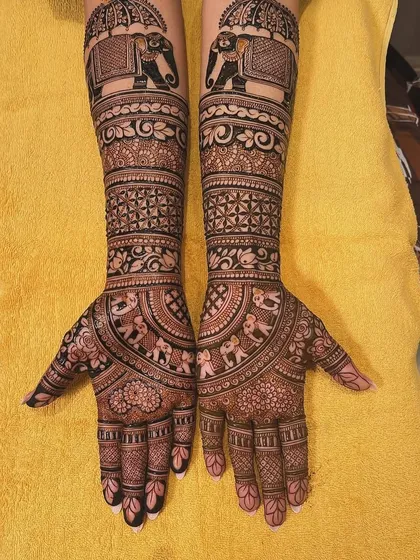 Full coverage bridal mehndi extending up the arms, featuring bands of different traditional patterns. You can see marching elephants, floral vines, and geometric checks, all coming together in a harmonious design.