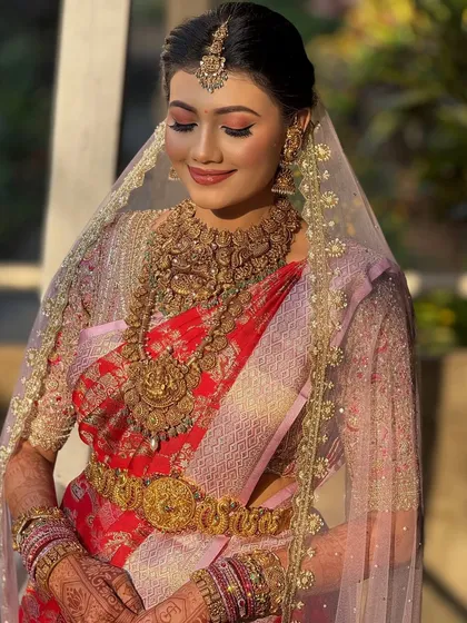 This bride is glowing under a sheer veil. The makeup is soft and romantic, with a focus on luminous skin and gentle pink tones on the eyes and lips.