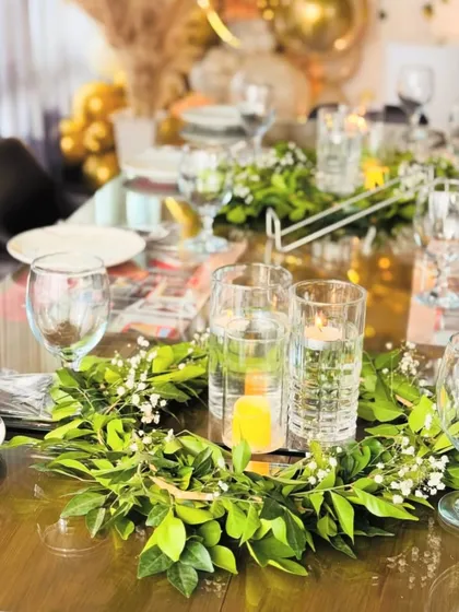 Another view of the elegant table setting, with clear glassware and lush green centerpieces.