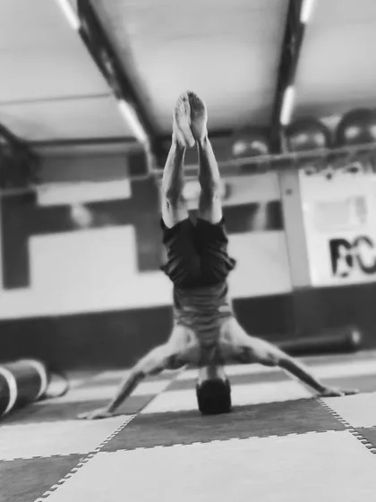 A clean, black and white shot of a tripod headstand. This inversion is fundamental for building the confidence and neck strength required for more advanced headstand variations.