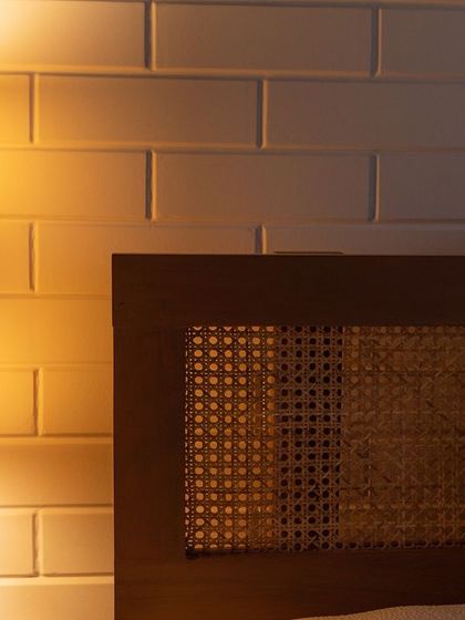 The right lighting can make a space come alive. This woven sconce casts a warm, diffused glow, complementing the texture of the cane headboard and the clean lines of the subway tiles.