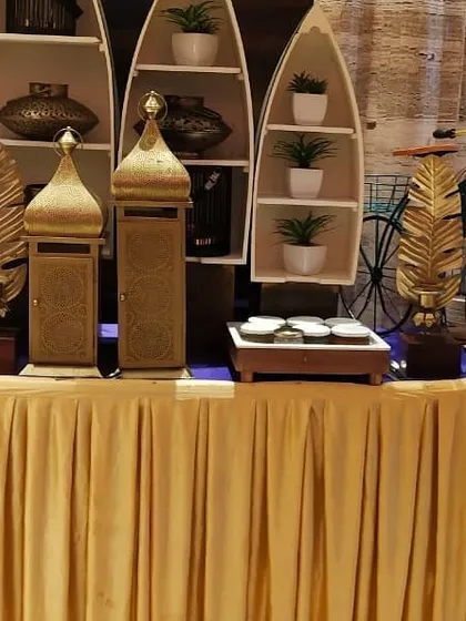 A creative and stylish buffet station from a festive event. The boat shaped shelves, golden decor pieces, and a decorative bicycle add a unique and personalized flair.