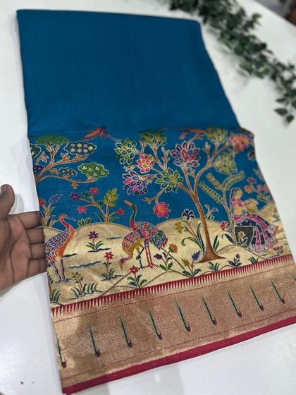 A beautiful teal blue Dola Paithani saree, showcasing the rich and detailed artistry of the Paithani weave.