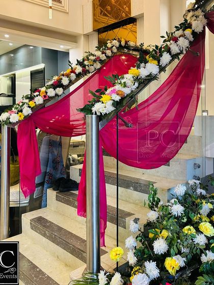 We carry the festive decor inside the home by decorating the staircase. The railing is beautifully wrapped with bright pink drapes and garlands of fresh, colorful flowers for the wedding celebration.