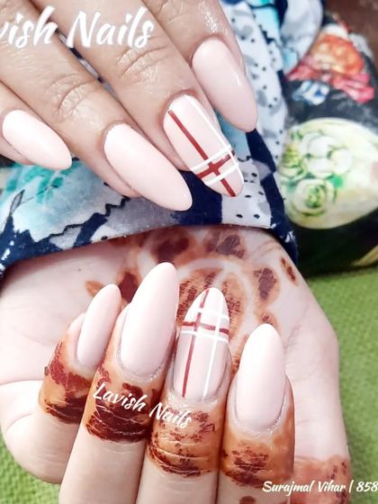 A lovely set of almond-shaped nails with a simple plaid-inspired accent nail, shown against a mehendi-decorated hand.