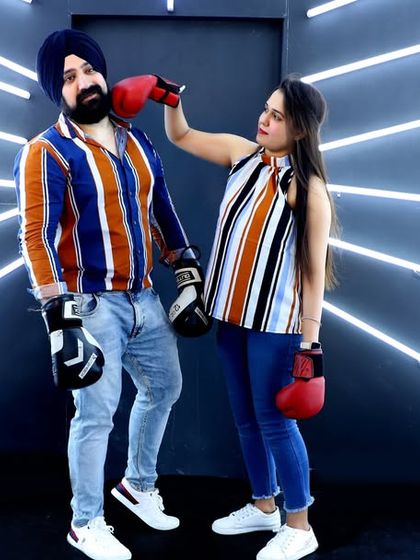 A playful and quirky pre-wedding photo using a boxing theme. The futuristic light tunnel background and boxing gloves make for a memorable and unconventional couple portrait.