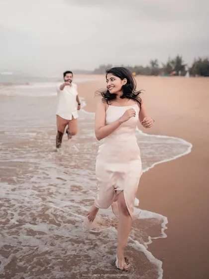 The pure, uninhibited joy of running along the shoreline. This candid shot from a Honnavara beach pre-wedding shoot captures the playful, carefree spirit of a couple's love story, with the ocean waves adding a sense of dynamic energy and freedom.