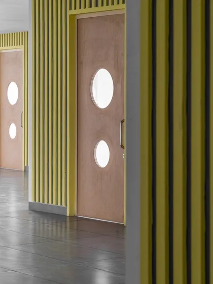 A detail of doorways at GD Goenka Public School, featuring circular windows and a ribbed wall texture. We weave wonder into the everyday with surprising details that spark curiosity.