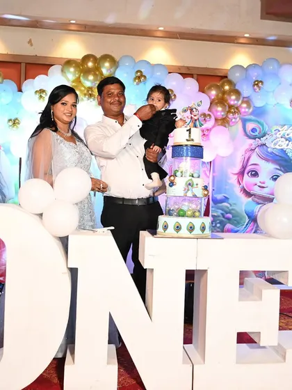 The family stands proudly with their son and his grand Krishna-themed cake.