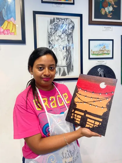 A participant proudly holds up her sunset canvas painting. The satisfaction of completing your own artwork is immense.
