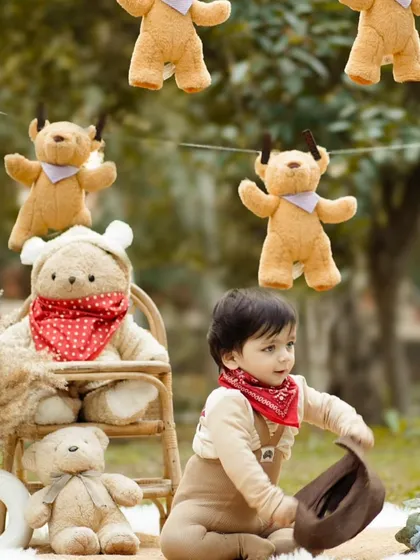 This little cowboy plays with his hat amidst a teddy bear-themed picnic. The candid nature of the shot captures his playful personality and the charm of the outdoor setup.